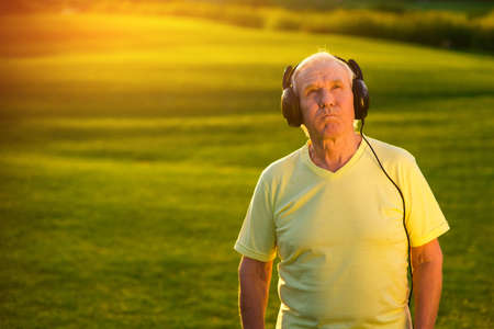 Elderly man in headphones. Person with serious face outdoor. Good music doesn't get old. Best rock ballads.の写真素材