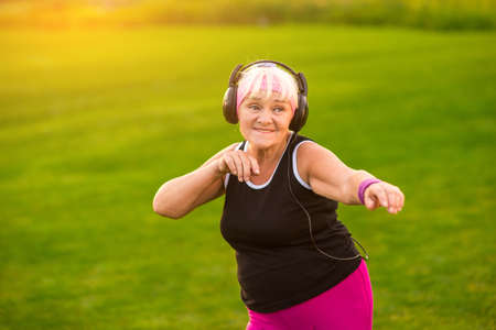 Senior woman with headphones. Elderly lady outdoor. Power of music. Hear the art.