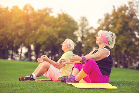 Elderly couple doing yoga. People sitting outdoor. Health of body and mind. Find balance inside yourself.の写真素材