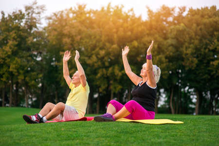 Senior couple does yoga. People sitting on mats outdoors. New hobby of grandparents. Good health and peaceful mind.の写真素材
