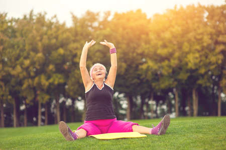 Woman with raised arms sitting. Lady with closed eyes outdoor. Concentrate and breathe deeply....