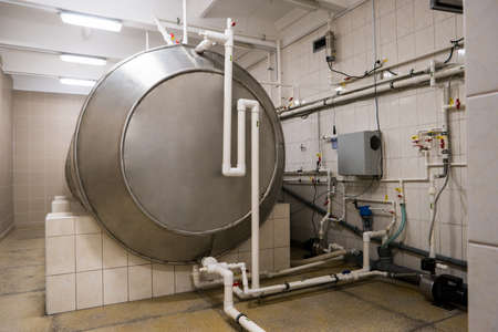 Horizontal storage tank. White pipes with valves. Water being purified at factory. New equipment with bigger capacity.の写真素材