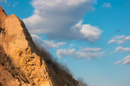 Birds flying near a mountain. Cloudy sky and rock. Sense the freedom. Long way to the goal.の写真素材