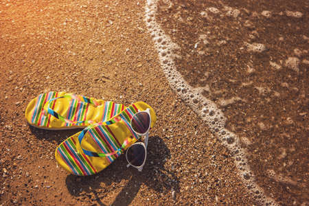 Flip flops with sunglasses. Footwear on a shore. Go to the sea. Spend holidays at tropical island.の写真素材