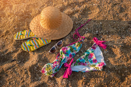 Hat and flip flops. Colorful swimsuit on sand. Be in style of summer. Get away from city bustle.の写真素材