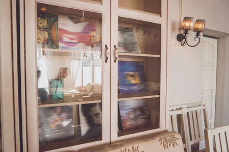Cupboard with glass doors. Covers with pictures. Collection of vinyl records. Music from good times.の写真素材
