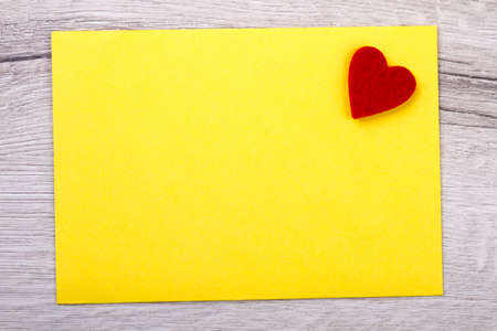 Yellow paper and heart. Small heart made of fabric. Celebrate day of love. Show your feelings.の写真素材