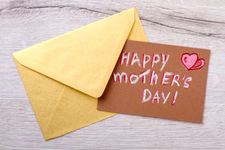 Mother`s day card and envelope. Envelope on wooden backdrop. Remember to send greeting. Congratulation letter for mom.の写真素材