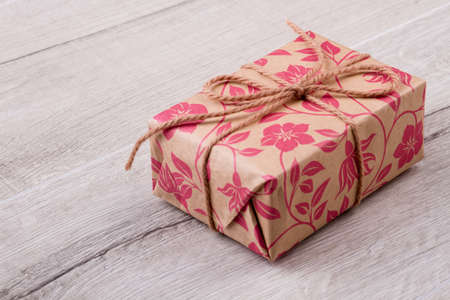 Present box on wooden background. Gift with rope bow. Give presents with joy. Design of holiday...