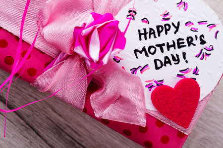 Happy Mother`s Day card inscription. Pink bow on gift box. Greeting handmade composition. Send best wishes.の写真素材