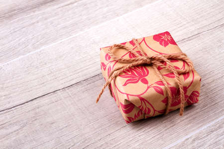 Box in wrap with rope. Gift lying on wooden surface. Tradition of sending gifts. Cute present for friend.の写真素材