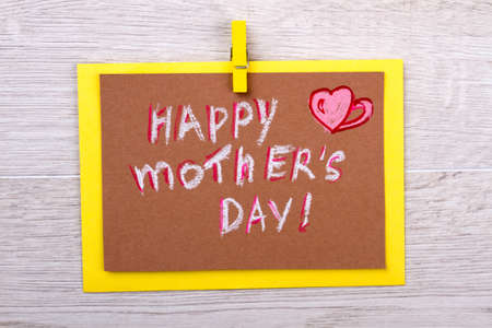 Congratulation card on Mother`s Day. Greeting card on wooden background. Mom will be happy. Happy...