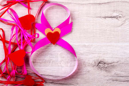 Tangled ribbon and hearts. 8-shaped riband on wooden background. Make every day like holiday. Inspiration for creation.の写真素材