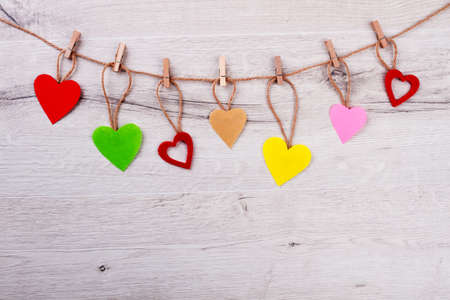 Hearts and clothespins on rope. Multicolor hearts on wooden background. Decorate room on holiday. Always stay positive.の写真素材