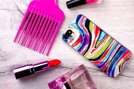 Smartphone and make-up. Perfume, lipstick and comb. Phone as modern accessory. Get ready for a party.の写真素材