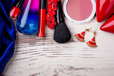 Female accessories on wooden background. Rouge, earrings and nail polish. Express your beauty.
