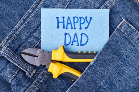 Dad's greeting paper and jeans. Pliers on pocket near card. How to congratulate father.の写真素材