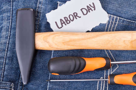 Labor Day card and instruments. Hammer and screwdriver on jeans. Traditions of celebration.の写真素材
