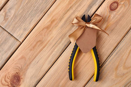 Pliers and blank greeting card. Paper with bow on wood. Irreplaceable tool at household.の写真素材