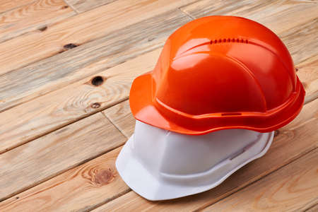 Safety helmets on wooden background. Orange and white hard hats. Rule number one is safety.の写真素材