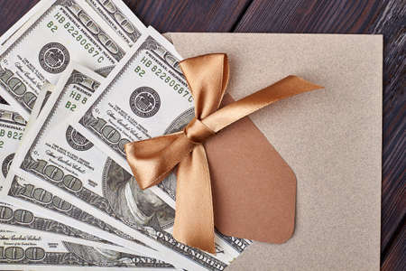 Blank greeting card and dollars. Ribbon bow on envelope. Money as modern idol.の写真素材
