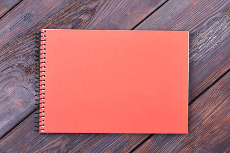 Notepad on wooden background. Peach colored notebook. Everyday life paper helper.の写真素材