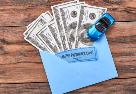 Plastic car, greeting card, money. Father's Day card on wood. Enough to buy a car.の写真素材