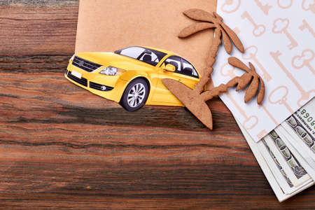 Cardboard car near palm tree. Dollars and key pattern paper. Exotic trip to happiness.の写真素材