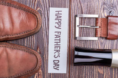 Belt and shoes on wood. Cologne near greeting card. Stylish accessory for father.の写真素材