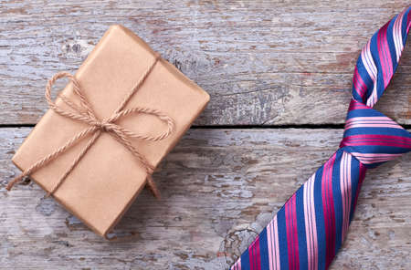 Gift box near striped necktie. Tie on wooden surface. How to choose a present.の写真素材