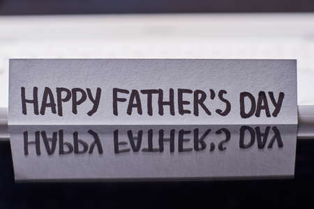 Reflection of Father's Day card. Greeting paper on black backdrop. Creative idea of congratulation.の写真素材