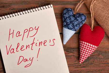 Valentines greeting paper on wood. Notepad and fabric hearts. How to make romantic surprise.の写真素材