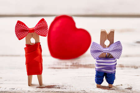 Red heart and clothespin couple. Heart on wooden background. Couple personalization by clothespins.の写真素材