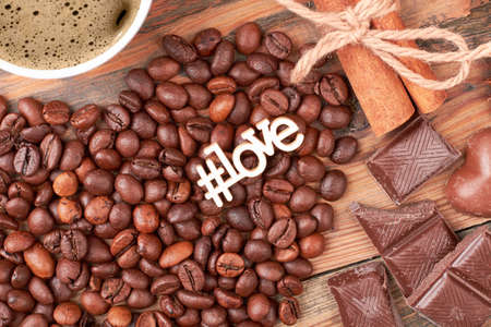 Hashtag love inscription near candies. Cinnamon sticks and coffee beans. Aromatic start of the day.