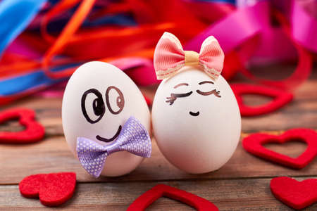 Love eggs and red hearts. Bows on eggs with faces. Art and food.の写真素材