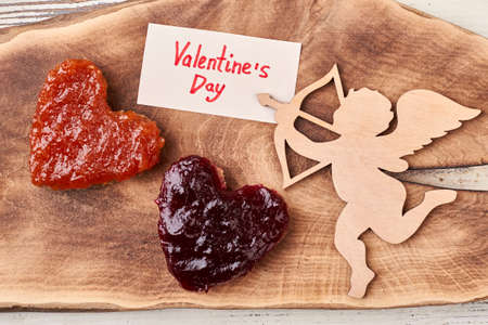 Cupid and Valentines Day paper. Bread with jam near card. Start morning with romance.