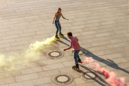 Couple is rollerblading. Colorful smoke coming from roller blade. Colorize the world.の写真素材