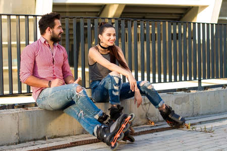 Couple on inline skates sitting. Smiling young woman. Good idea for first date.の写真素材