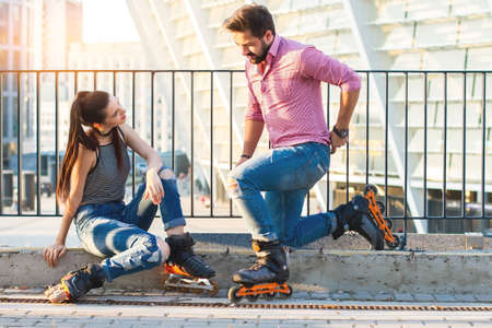 Couple wearing roller blade. Man kneeling before woman. Find a common hobby.の写真素材