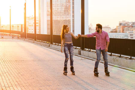 People holding hands and rollerblading. Smiling couple at sunrise. Hold my hand.の写真素材