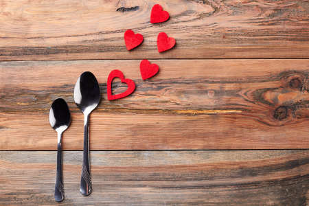 Teaspoons near red hearts. Silver spoons on wooden background. Being always together.の写真素材