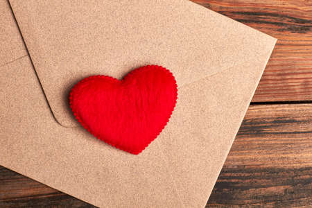 Red heart on envelope. Letter with heart on wood. Send love receive love.の写真素材