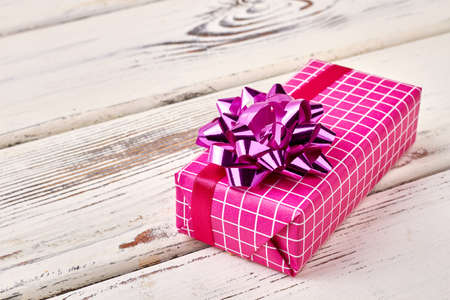 Pink gift box with bow. Present box on wooden backdrop. How to decorate a present.の写真素材