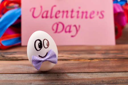 Valentines Day card near egg. Egg with face and bow. Cute surprise for beloved.の写真素材