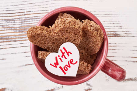 With love card in cup. Mug with bread on wood. Pretty way to serve bread.の写真素材