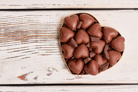 Heart-shaped box with chocolates. Candies on wooden surface. Joy for the whole day.の写真素材