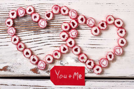 Red greeting card and candies. Sweets in shape of heart. Way to confess in love.の写真素材