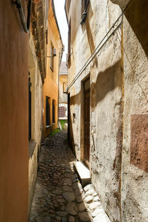 Narrow path between houses. Old walls and sunlight. One way to go.の写真素材