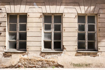 Damaged wall with windows. Part of aged building. Impact of time on architecture.