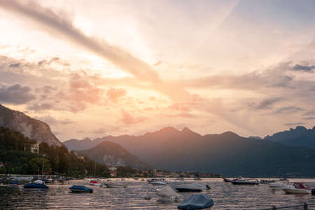 Boats, mountains and sky. Water and town at distance. Maggiore lake at sunrise.